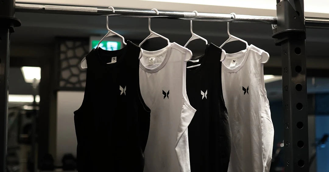 Shapeshift black and white gym tank tops for men, minimalist muscle-fit workout shirts made with premium breathable fabric. Sleek performance activewear designed for gym training, bodybuilding, and fitness style. Shapeshift gym wear brand focuses on comfort, detail, and confidence through minimalist athletic design.